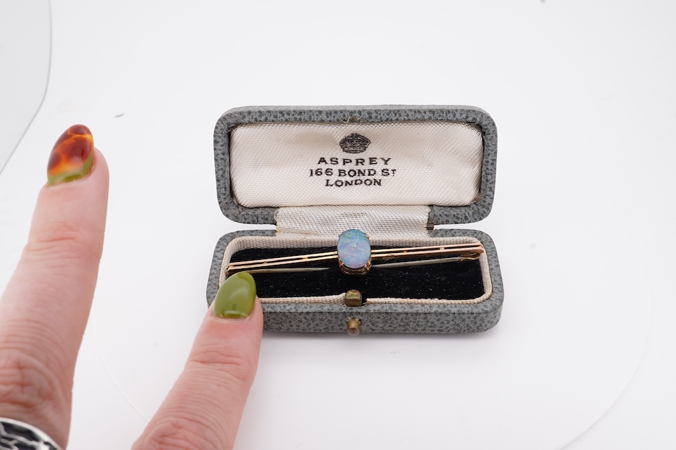An early 20th century 9ct and single stone oval black opal doublet set bar brooch, 57mm, gross weight 2.3 grams, in an Asprey box. Condition - fair
